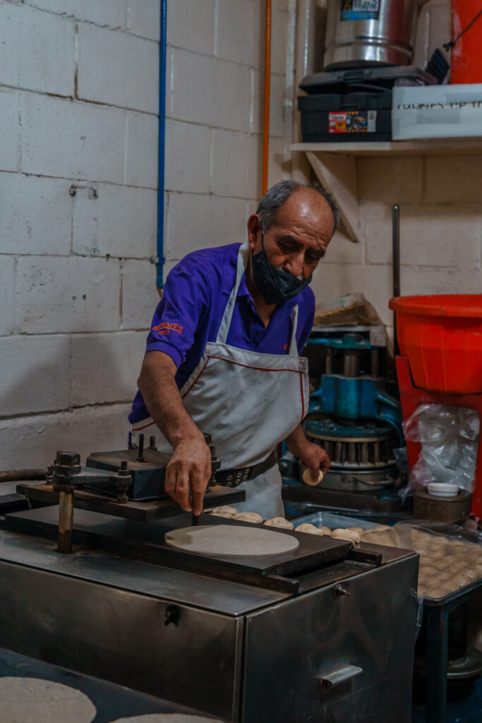 Man making fresh tortillas at Mercado Medellin.